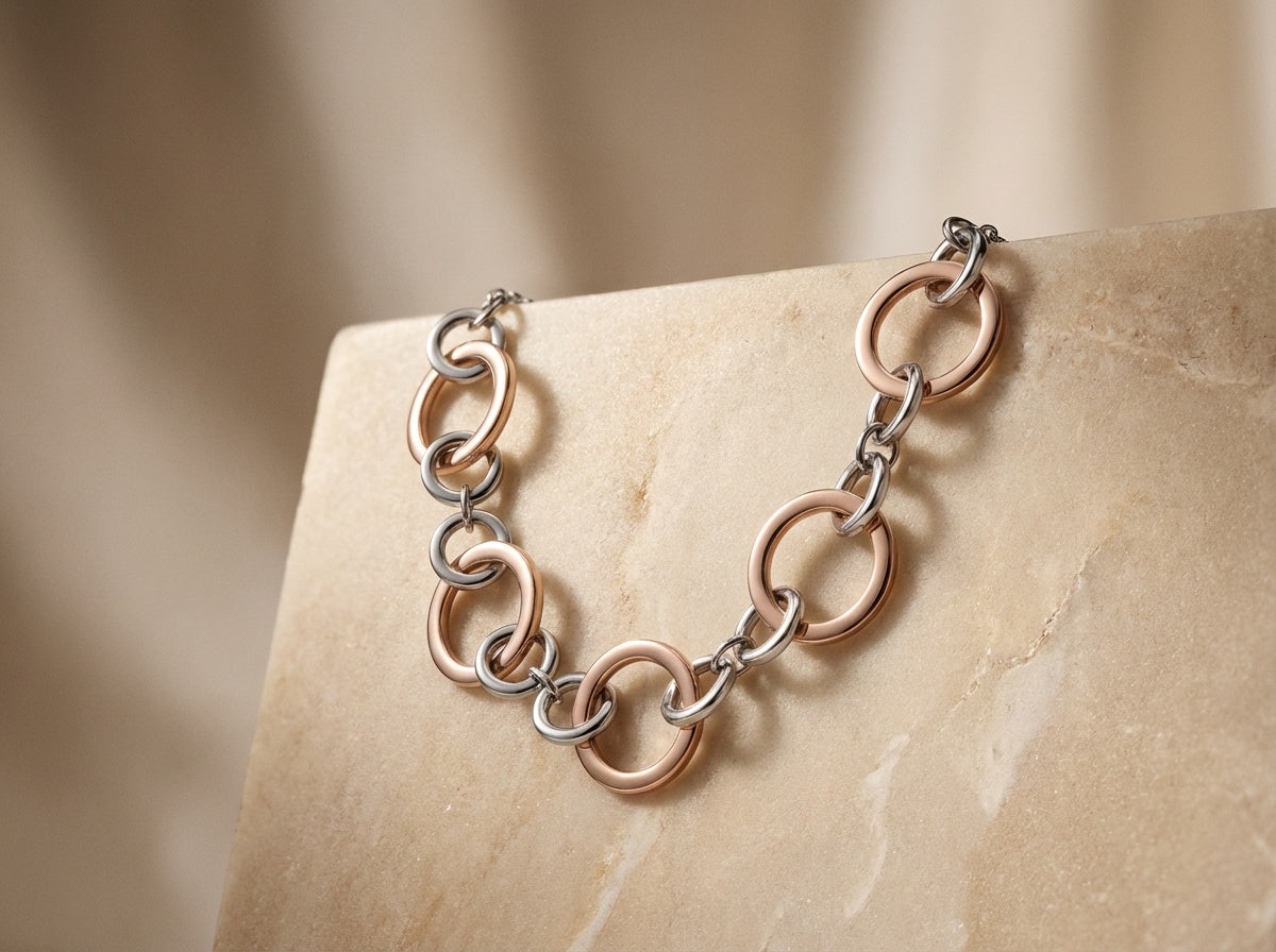 Gold and silver chain necklace on a beige stone surface