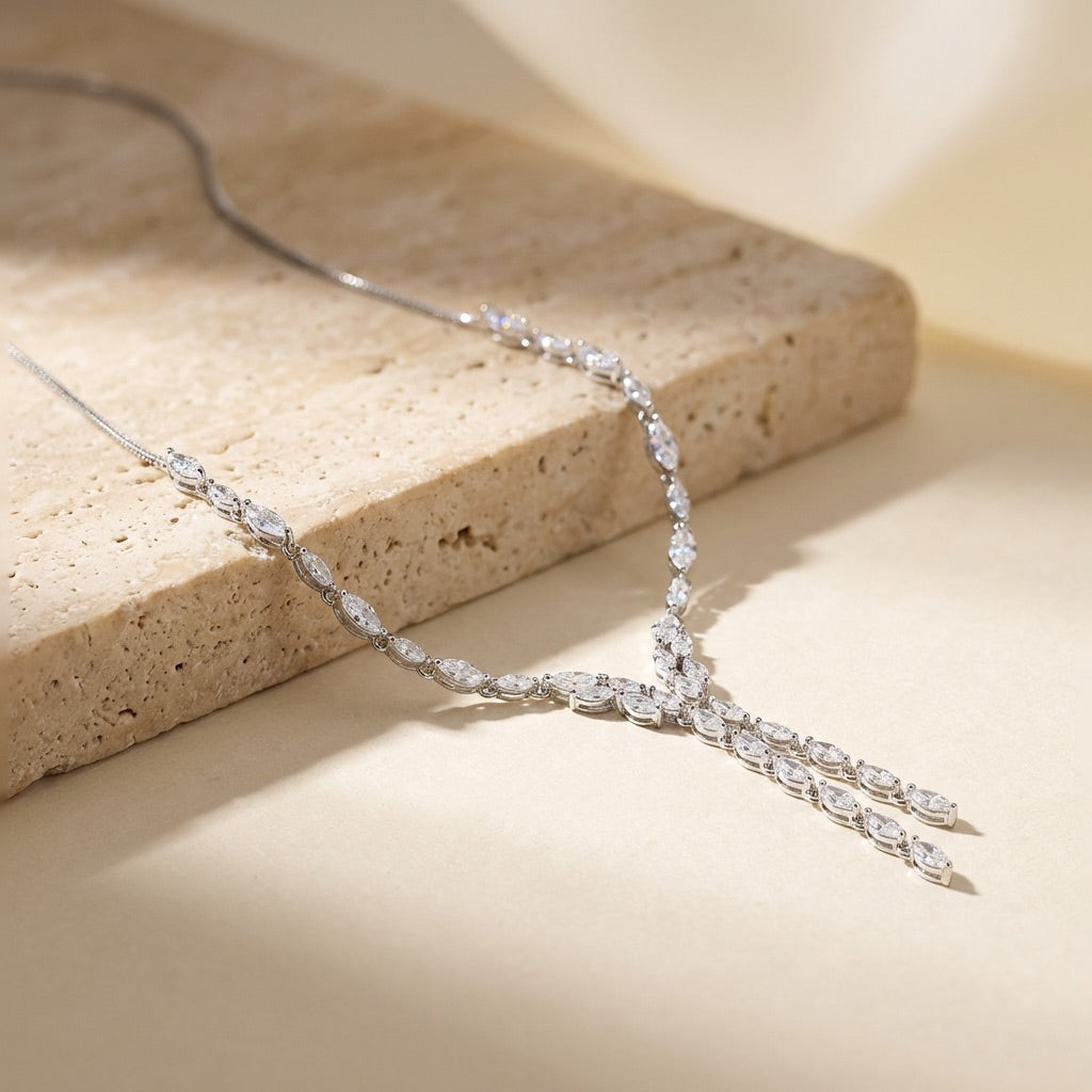 Silver necklace with clear stones on a beige stone surface
