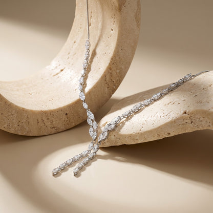 Silver necklace with marquise-shaped diamonds on a beige stone surface