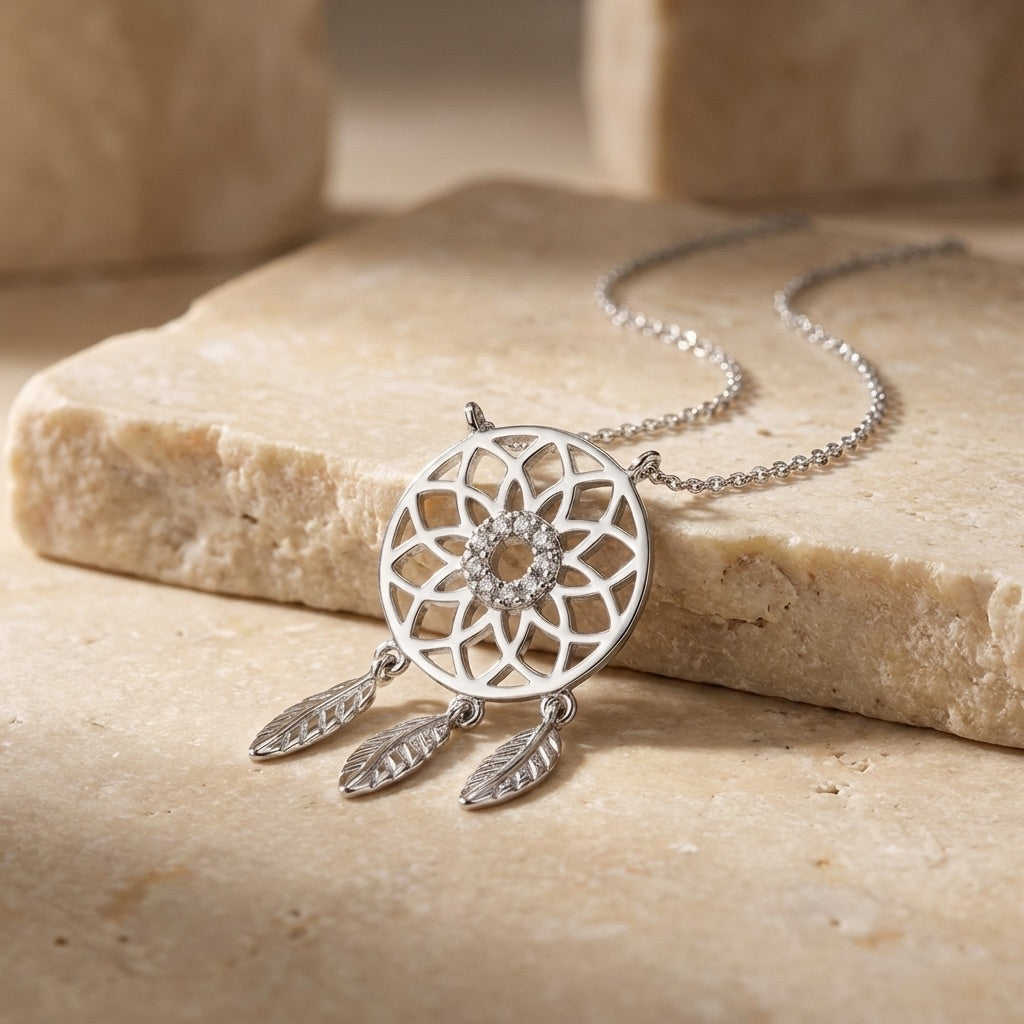 Silver dreamcatcher necklace on a stone surface