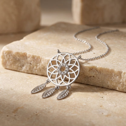 Silver dreamcatcher necklace on a stone surface