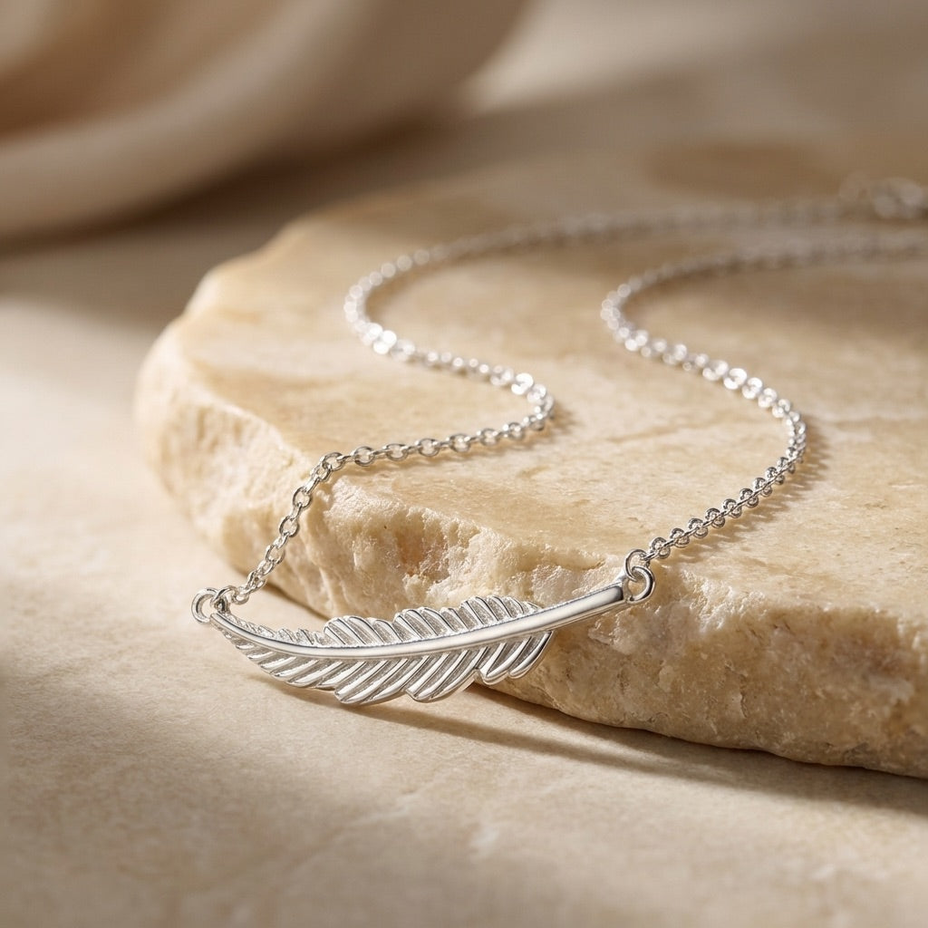 Silver feather necklace on a stone surface