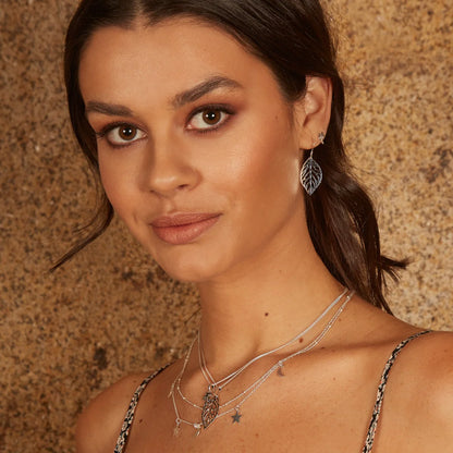 Woman wearing silver jewelry against a textured brown background