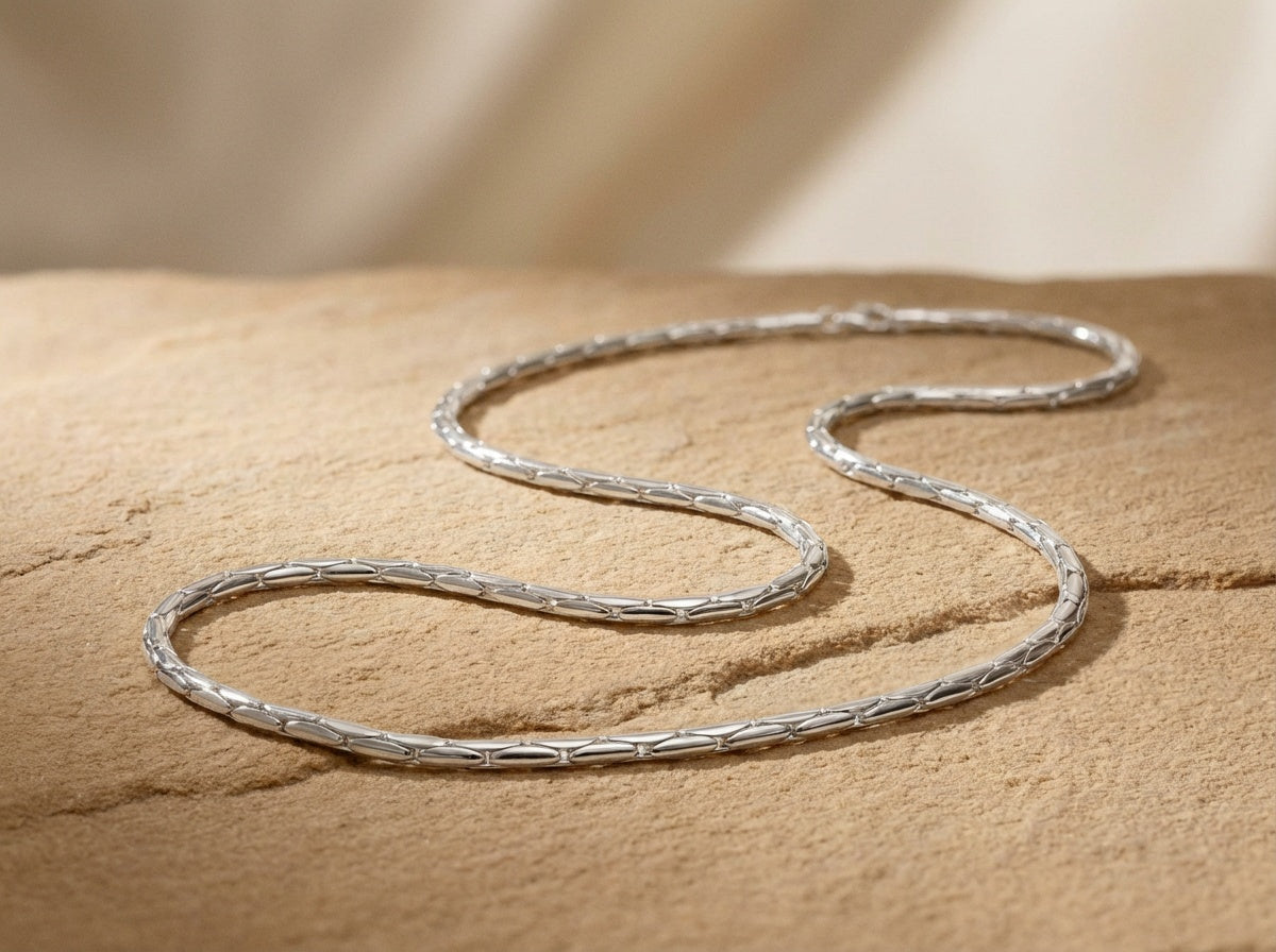 Silver snake chain  necklace on a textured beige surface