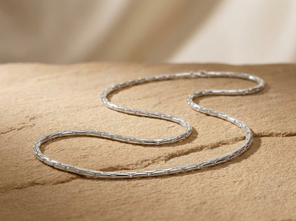 Silver snake chain  necklace on a textured beige surface