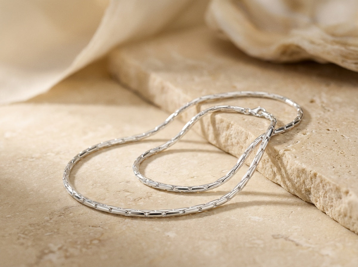 Silver necklace on a textured beige surface