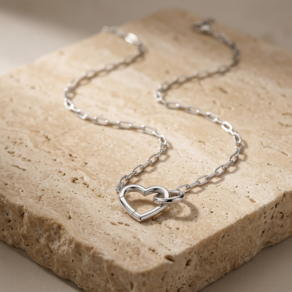 Silver heart-shaped necklace on a textured stone surface