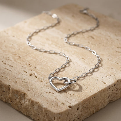 Silver heart-shaped necklace on a textured stone surface