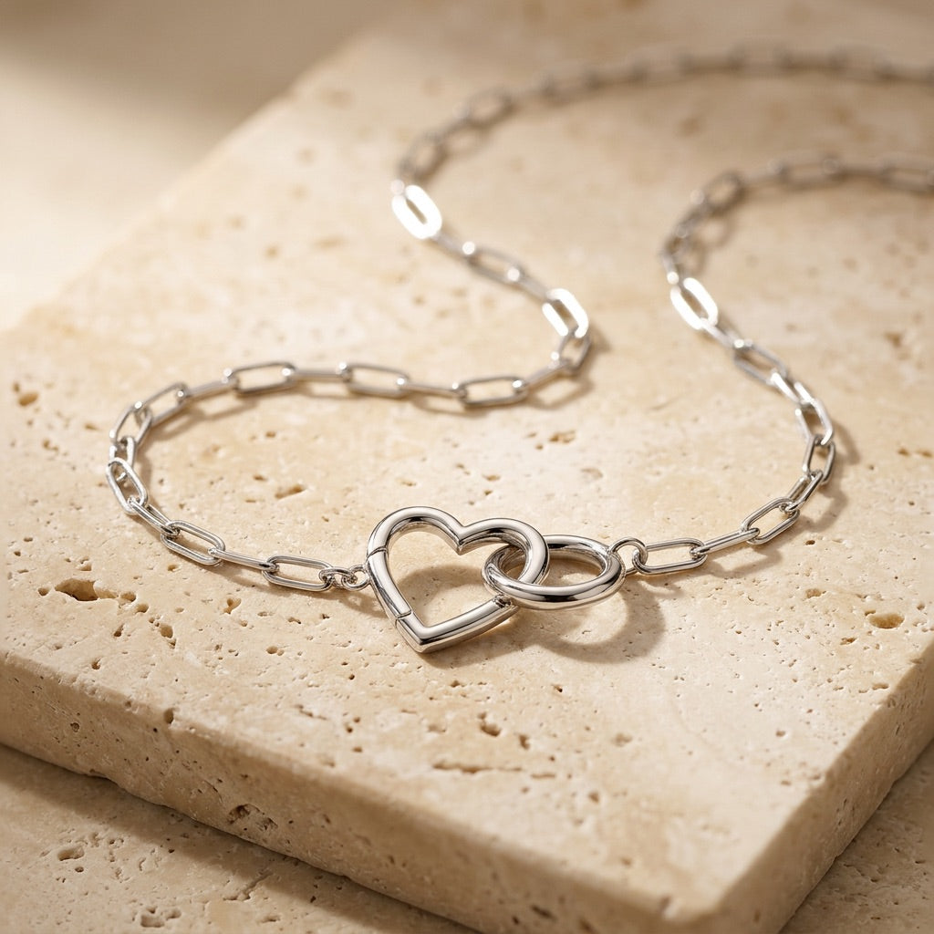 Silver chain bracelet with a heart design on a beige stone surface