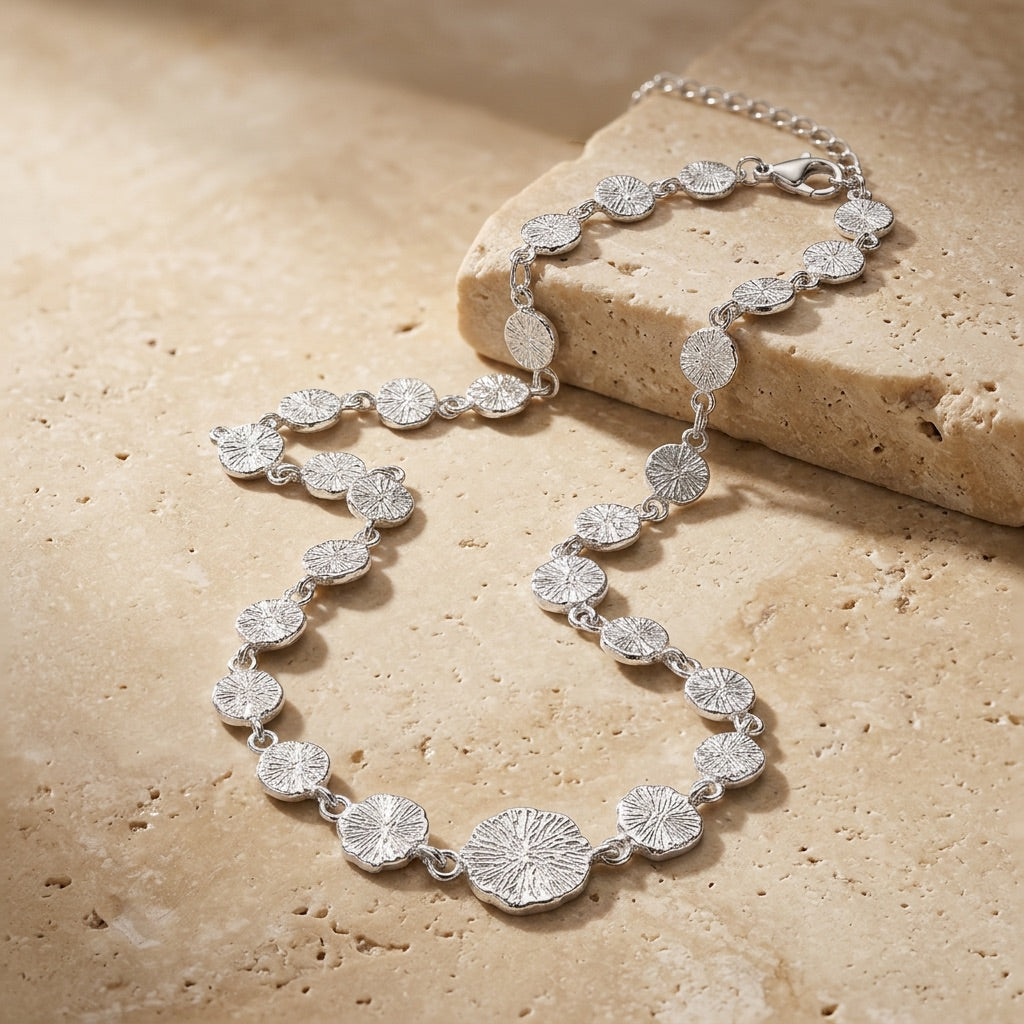Silver bracelet with floral designs on a beige stone surface