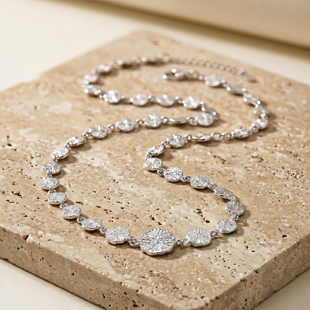 Silver necklace on a textured stone surface
