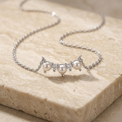 Pearl necklace with silver chain on a beige stone surface