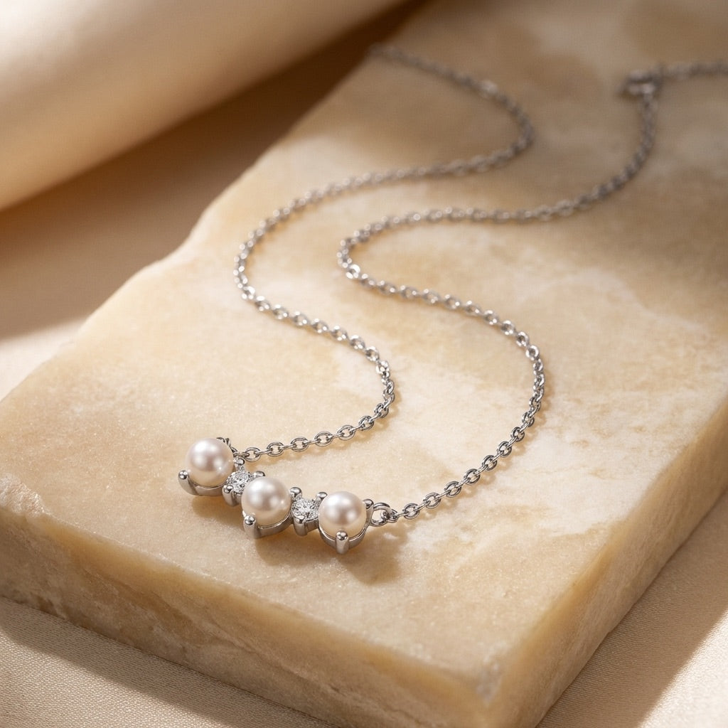 Silver necklace with pearls on a beige stone surface