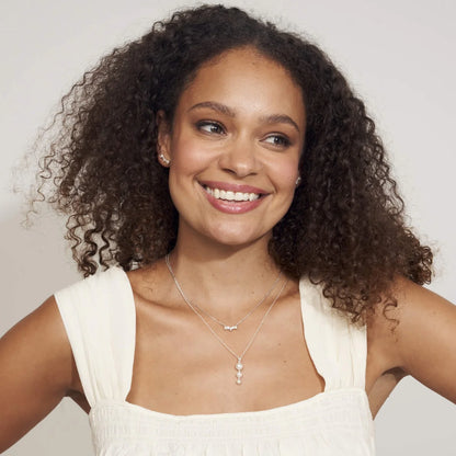 Woman wearing a white sleeveless top with a plain background wearing aCurved Freshwater Pearl and Cubic Zirconia Bar Necklace