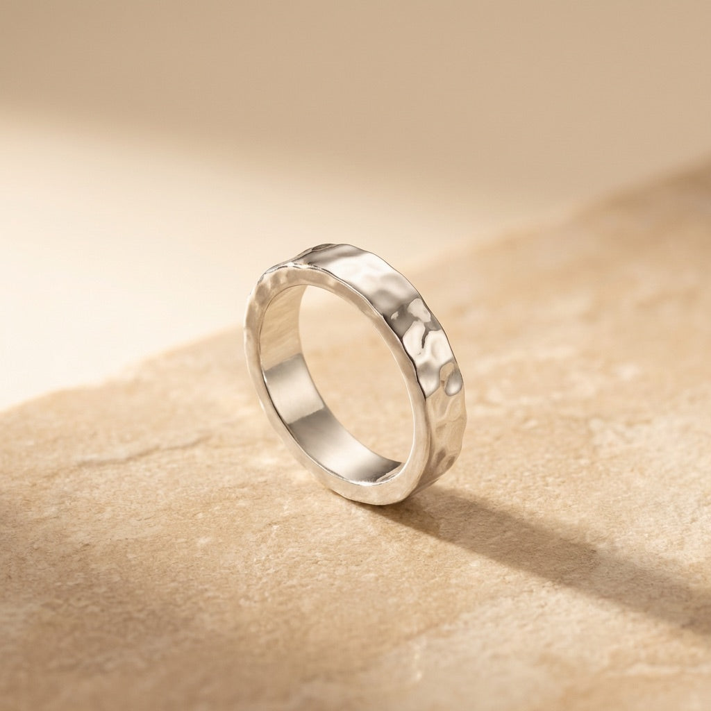 Silver ring on a beige stone surface