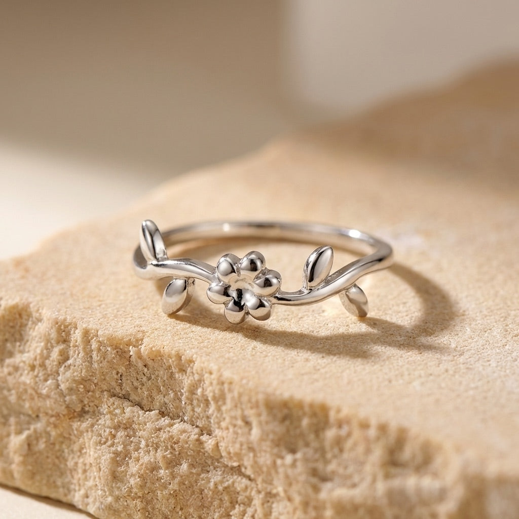 Silver ring with floral design on a beige stone surface