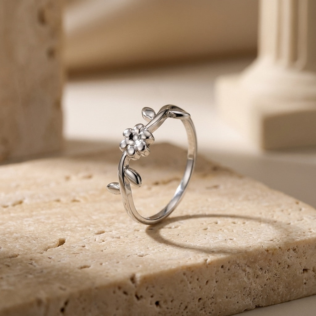 Silver ring with floral design on a beige stone surface