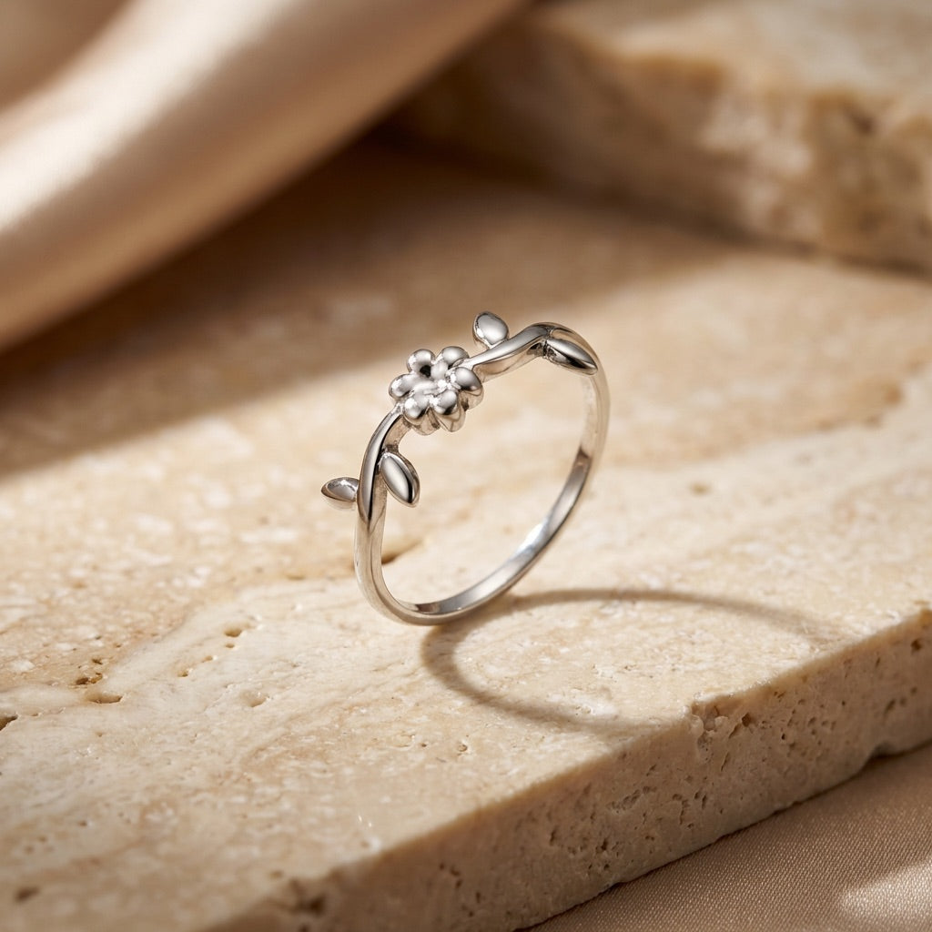 Silver ring with floral design on a beige stone surface