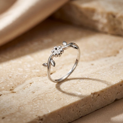 Silver ring with floral design on a beige stone surface