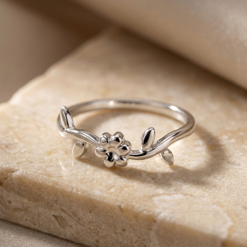 Silver ring with floral design on a beige stone surface