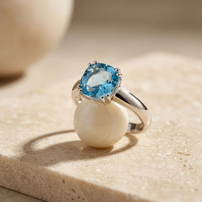 Silver ring with a blue gemstone on a beige surface
