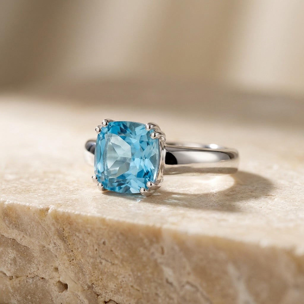 Silver ring with a blue gemstone on a beige stone surface