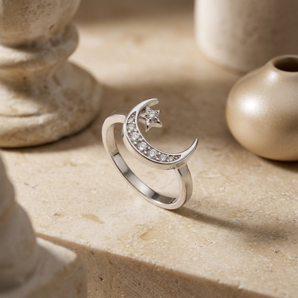 Silver ring with moon and star design on a stone surface