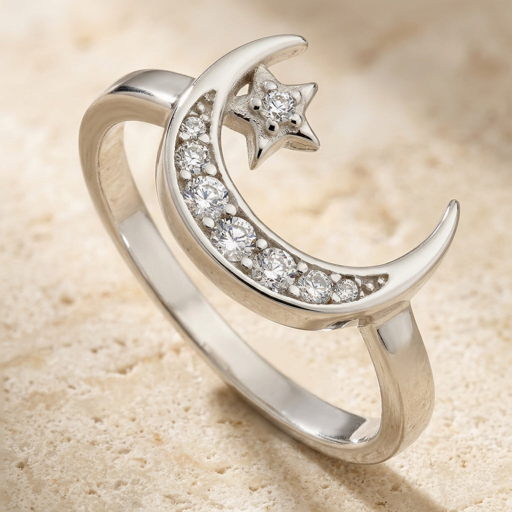 Silver ring with moon and star design on a beige background