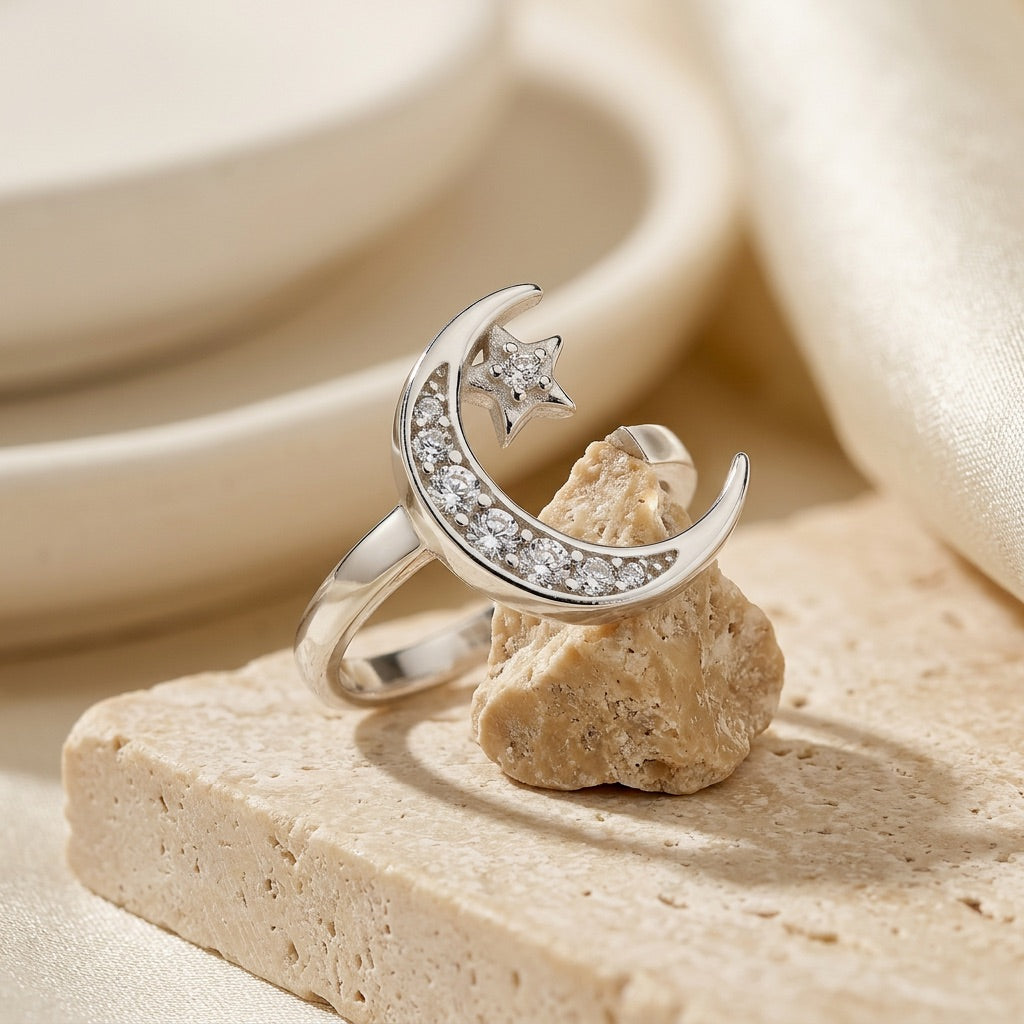 Silver ring with moon and star design on a stone surface