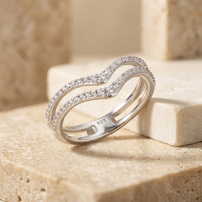 Silver ring with diamonds on a beige stone surface