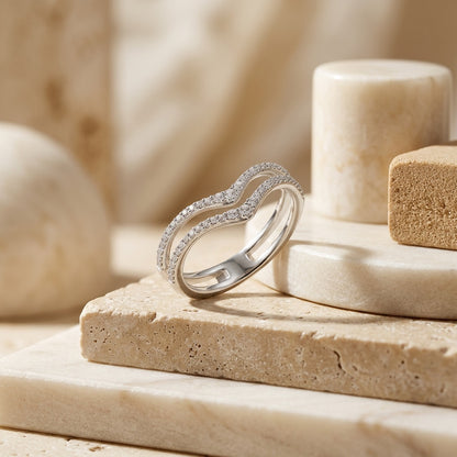 Silver ring with small diamonds on a beige stone surface