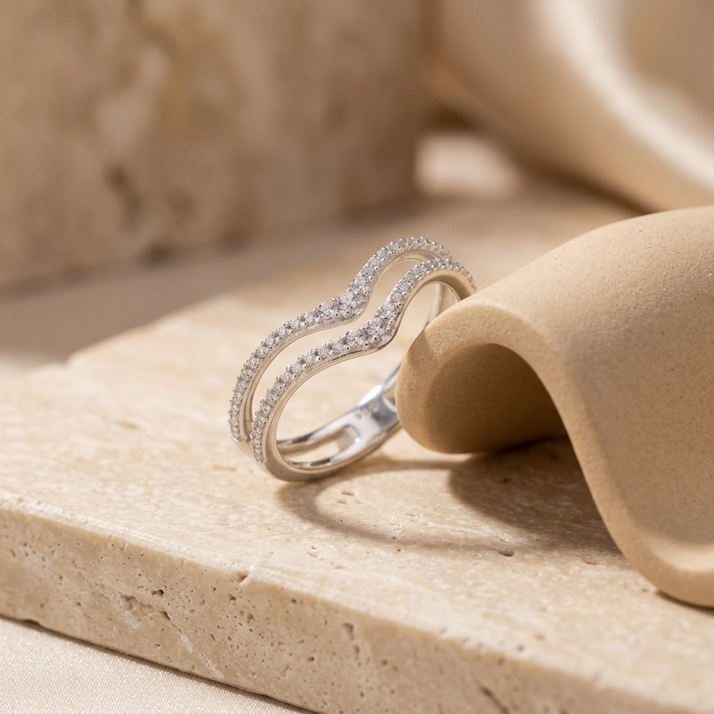 Silver ring with diamonds on a beige stone surface