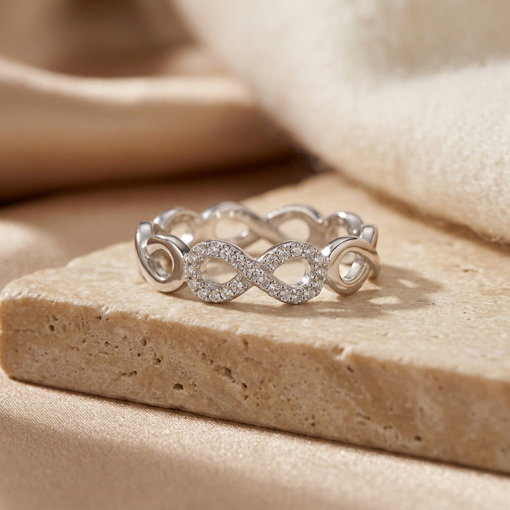 Silver infinity ring on a beige stone surface