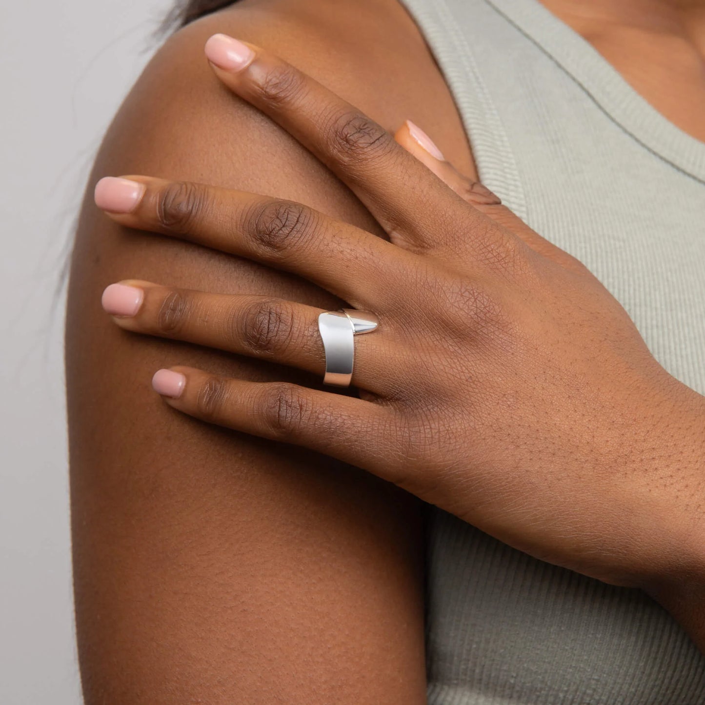 Hand wearing a Silver Wrap Ring on a neutral background
