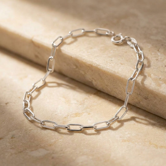 Silver chain bracelet on a beige stone surface